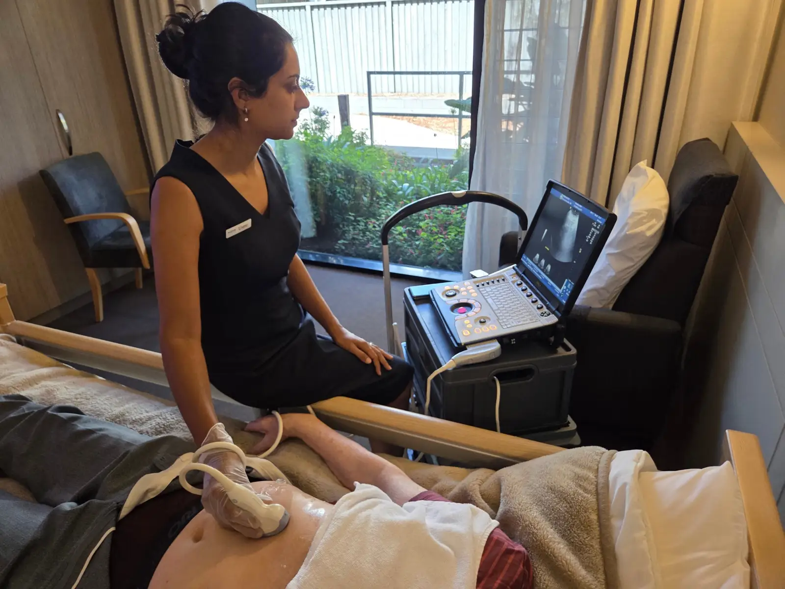 Sonographer performing a bedside ultrasound, captured on site